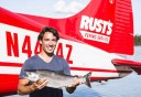Photo of guest showing off fish in front of seaplane